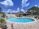 Backyard view of a kidney-shaped pool with brick pavers, white fence, and patio area at 9631 Oak Ne St, St Petersburg, FL 33702