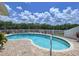 A kidney-shaped pool surrounded by brick pavers and a white fence under a blue sky at 9631 Oak Ne St, St Petersburg, FL 33702