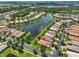 Aerial view of home with community lake, mature landscaping, and a neighborhood street at 16227 Cape Coral Dr, Wimauma, FL 33598
