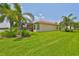 Well maintained lawn with tropical landscaping, screened lanai, and red tile roof, providing a serene outdoor space at 16227 Cape Coral Dr, Wimauma, FL 33598