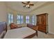 Cozy bedroom with tray ceiling, chair, armoire, and a window overlooking a garden, offering a relaxing retreat at 16227 Cape Coral Dr, Wimauma, FL 33598