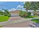 Charming single-story home with a two car garage, brick driveway, and tropical landscaping at 16227 Cape Coral Dr, Wimauma, FL 33598