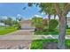 Well-maintained home with tropical landscaping, mature trees, and a brick driveway at 16227 Cape Coral Dr, Wimauma, FL 33598