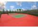 Outdoor red tennis court with green surface and netting at 16227 Cape Coral Dr, Wimauma, FL 33598
