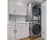 A modern laundry room featuring a stacked washer and dryer, and white cabinetry at 1 Beach Se Dr # 1902, St Petersburg, FL 33701
