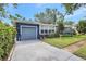 The blue house has a well-kept lawn, colorful flowers, and an attached garage, with a long driveway at 1115 45Th N St, St Petersburg, FL 33713