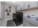 Functional laundry room with modern washer and dryer, gray cabinets, and ample storage at 11320 Chilly Water Ct, Riverview, FL 33569