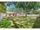 Spacious backyard with lush green grass, mature trees for shade, a white fence, and a wooden deck with outdoor seating at 11510 92Nd Way, Largo, FL 33773