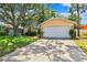Well-maintained home featuring a lush green lawn, mature trees and a two-car garage at 11510 92Nd Way, Largo, FL 33773