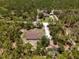 A distant aerial view shows a home surrounded by a dense forest with a detached garage at 12090 Thames Ave, Weeki Wachee, FL 34614