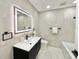 Modern bathroom features sleek vanity, illuminated mirror, and stone-style tile at 1290 Michigan Blvd, Dunedin, FL 34698