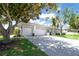 Charming home exterior featuring a three-car garage and a lush, mature tree in the front yard at 137 Woodcreek E Dr, Safety Harbor, FL 34695