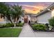 Well-manicured lawn and landscaped garden leading to the front entrance with a red door and arched windows at 137 Woodcreek E Dr, Safety Harbor, FL 34695