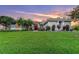 Charming home featuring lush green lawn, mature trees, and a red front door, under a lovely pastel sunset sky at 137 Woodcreek E Dr, Safety Harbor, FL 34695
