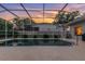 Screened-in pool reflecting a beautiful sunset sky with manicured landscaping at 137 Woodcreek E Dr, Safety Harbor, FL 34695