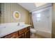 Full bathroom featuring green wallpaper, a shower/tub combo, and a vanity sink with storage at 1648 Concord St, Dunedin, FL 34698