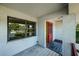 Covered front porch with a large window and a red door at 1648 Concord St, Dunedin, FL 34698