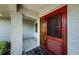 Covered front porch featuring a decorative red door and neutral toned walls at 1648 Concord St, Dunedin, FL 34698