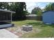 An expansive backyard has a firepit, a blue shed for storage, and lots of green grass for playing and relaxing at 1665 Grove St, Clearwater, FL 33755