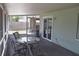 A screened-in lanai features stone floors with table and chairs, as well as a sliding glass door and backyard views at 1665 Grove St, Clearwater, FL 33755