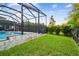 Landscaped backyard featuring lush grass, a pool, and a screened enclosure, perfect for enjoying the outdoors at 17589 Cruiser Bnd, Land O Lakes, FL 34638