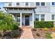 Front porch with a brick walkway, small palms, and a dark front door at 17589 Cruiser Bnd, Land O Lakes, FL 34638