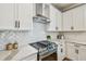 Modern kitchen with herringbone backsplash, white cabinets, stainless steel stove, and marble countertops at 17589 Cruiser Bnd, Land O Lakes, FL 34638