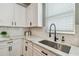 Modern kitchen with white cabinets, marble countertops, black faucet, herringbone backsplash and stainless sink at 17589 Cruiser Bnd, Land O Lakes, FL 34638