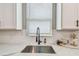 Modern kitchen with white cabinets, marble countertops, black faucet, and herringbone backsplash at 17589 Cruiser Bnd, Land O Lakes, FL 34638
