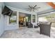 Screened patio featuring ceiling fan, tv, tile floor, and access to the kitchen and backyard at 17589 Cruiser Bnd, Land O Lakes, FL 34638