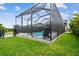Backyard view of the sparkling pool and screened enclosure with lush green grass and a chair, perfect for relaxing at 17589 Cruiser Bnd, Land O Lakes, FL 34638