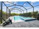 Enclosed pool and spa with lighting, outdoor seating, and lush greenery at 17589 Cruiser Bnd, Land O Lakes, FL 34638