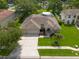 Aerial view of a well-maintained home with a spacious driveway, lush lawn, and mature trees at 18518 Bittern Ave, Lutz, FL 33558