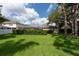 Large grassy backyard with a view of the screened pool enclosure and mature landscaping, offering privacy and relaxation at 18518 Bittern Ave, Lutz, FL 33558