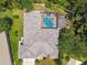 Aerial view of a well-maintained home with a screened-in pool, surrounded by lush greenery and ample backyard space at 1877 Muirfield Way, Oldsmar, FL 34677