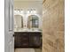 Modern bathroom features double sinks with gold faucets and unique travertine-style brick wall at 1877 Muirfield Way, Oldsmar, FL 34677