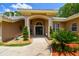Attractive front entrance with lush landscaping and a covered entry with double doors at 1877 Muirfield Way, Oldsmar, FL 34677