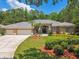 Charming home exterior with landscaped yard, spacious driveway, and palm trees at 1877 Muirfield Way, Oldsmar, FL 34677