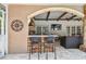 Outdoor kitchen featuring a stone bar, granite countertop, seating, a large TV, and a built-in grill is great for entertaining at 1877 Muirfield Way, Oldsmar, FL 34677