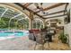 Outdoor entertaining area featuring a built-in grill and a screened-in pool with lounge furniture at 1877 Muirfield Way, Oldsmar, FL 34677