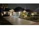 Charming single-story home exterior, warmly lit with manicured landscaping and an American flag at night at 2121 Worthington Greens Dr, Sun City Center, FL 33573