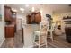 Eat-in kitchen with wood cabinets, pendant lighting, wood floors, and white bar stools at 2121 Worthington Greens Dr, Sun City Center, FL 33573