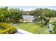 Aerial view of a charming yellow home with lush landscaping, a pond, and a fenced yard at 2174 62Nd N St, Clearwater, FL 33760