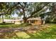 Exterior view of a single-story yellow house with a large tree in the front yard at 2174 62Nd N St, Clearwater, FL 33760