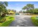 Wide view of a colorful home with a long driveway and mature trees at 2174 62Nd N St, Clearwater, FL 33760
