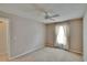 Neutral carpeted bedroom features a ceiling fan, a window with curtains, and a door to hallway at 2527 Wrencrest Cir, Valrico, FL 33594