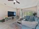 Bright living room with large TV, fireplace, comfortable blue sectional, and sliding door to the lanai at 31201 Shaker Cir, Wesley Chapel, FL 33543