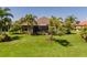 Beautiful backyard showcasing a lush lawn, tropical landscaping, and a screened-in lanai, perfect for relaxing and entertaining outdoors at 347 Cockle Shell Loop, Apollo Beach, FL 33572