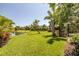 Expansive green backyard featuring lush grass, beautiful landscaping, and a tranquil pond view, offering a serene outdoor space at 347 Cockle Shell Loop, Apollo Beach, FL 33572