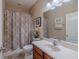 Cozy bathroom featuring a shower-tub combo with decorative curtain and a wood-finish vanity at 347 Cockle Shell Loop, Apollo Beach, FL 33572